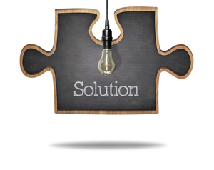 Solution concept on puzzle shape black blackboard with light bulb hanging